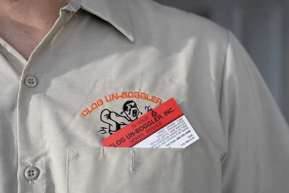 Clog Un-Boggler embroidery and a business card tucked into a work-shirt pocket.