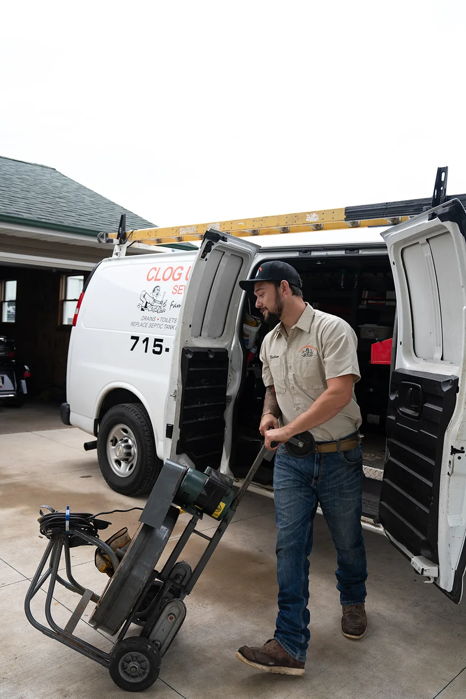Nathan moving a large cable machine beside the open Clog Un-Boggler service van.